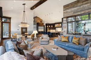 Living room with an inviting chandelier, beamed ceiling, high vaulted ceiling, and hardwood / wood-style flooring