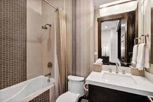 Full bathroom with toilet, shower / bath combo with shower curtain, and vanity