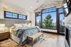 Bedroom featuring multiple windows, high vaulted ceiling, and wood-type flooring