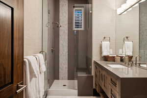 Bathroom featuring a shower with shower door and vanity