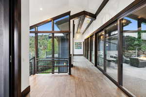 Hallway with hardwood / wood-style floors and lofted ceiling with beams