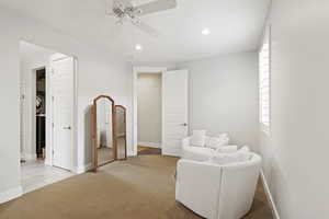 Living area featuring light colored carpet and ceiling fan