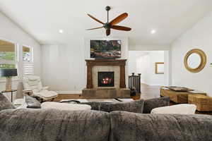 Living room featuring vaulted ceiling, hardwood / wood-style flooring, ceiling fan, and a tile fireplace