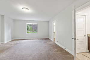 Empty room with light colored carpet and a textured ceiling