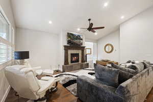 Living room with ceiling fan, a tiled fireplace, and dark hardwood / wood-style floors