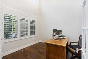 Home office with a wealth of natural light and dark wood-type flooring