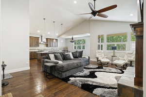 Living room with dark wood-type flooring, ceiling fan, high vaulted ceiling, and sink