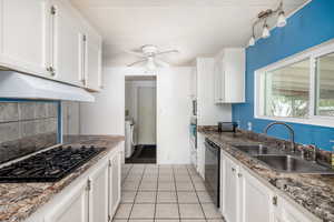 Kitchen featuring white cabinets, black appliances, sink, ceiling fan, and light tile patterned flooring