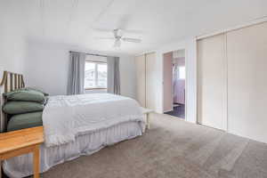 Bedroom featuring carpet flooring, ceiling fan, ensuite bathroom, and multiple closets