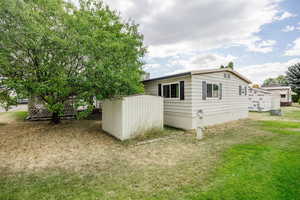 View of side of property featuring a storage unit, central AC unit, and a yard