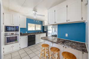 Kitchen with a kitchen breakfast bar, sink, ceiling fan, appliances with stainless steel finishes, and white cabinets