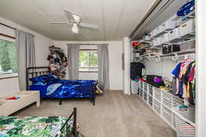 Bedroom featuring a textured ceiling, ceiling fan, and carpet