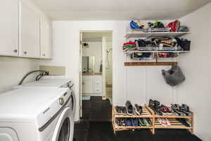 Laundry room featuring washing machine and clothes dryer, cabinets, and a textured ceiling