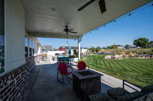 View of back patio with ceiling fan and an outdoor fire pit.