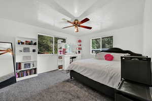 Bedroom featuring a textured ceiling, carpet flooring, ceiling fan, and multiple windows