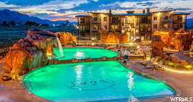 Community Pool at dusk with pool water feature and a patio area