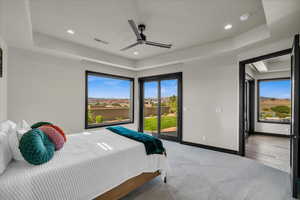 Bedroom featuring access to exterior, ceiling fan, a raised ceiling, and light hardwood / wood-style flooring