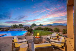 Pool at dusk with a patio, a mountain view, and an outdoor living space with a fire pit