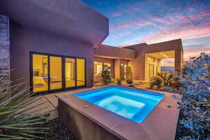 Pool at dusk featuring an in ground hot tub and a patio