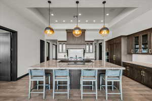 Kitchen with decorative light fixtures, a large island, and a raised ceiling