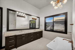 Bathroom with vanity, a chandelier, and a bathing tub