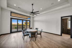 Dining area featuring light wood-type flooring and a tray ceiling