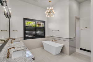 Bathroom featuring a bathing tub, a chandelier, and vanity