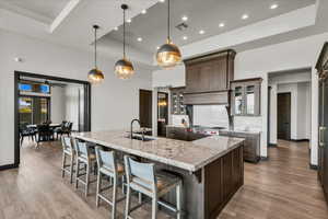 Kitchen featuring light stone countertops, decorative light fixtures, light hardwood / wood-style floors, sink, and a large island