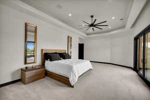 Bedroom featuring access to exterior, ceiling fan, light carpet, and a tray ceiling