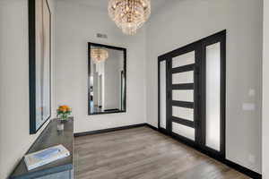 Foyer entrance featuring light hardwood / wood-style floors and an inviting chandelier