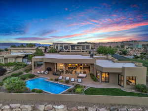 Back house at dusk featuring an outdoor bar, an outdoor living space, and a patio area