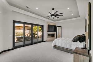 Carpeted bedroom with access to exterior, ceiling fan, and a raised ceiling