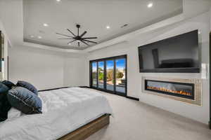 Carpeted bedroom featuring a raised ceiling and access to exterior