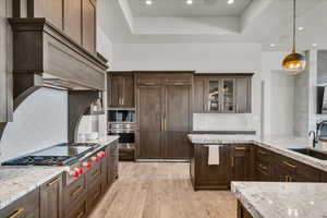 Kitchen with light stone counters, sink, decorative light fixtures, and light hardwood / wood-style floors