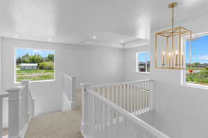 Corridor with a textured ceiling, a raised ceiling, and carpet floors