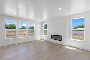 Unfurnished living room featuring a textured ceiling, light hardwood / wood-style floors, and a fireplace