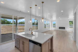 Kitchen featuring a center island with sink, dishwasher, sink, and light hardwood / wood-style flooring