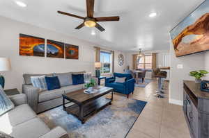 Living room with ceiling fan and light tile patterned flooring