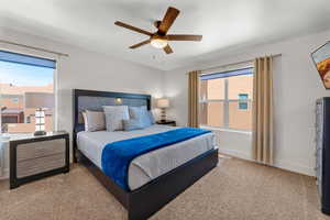 Carpeted bedroom with multiple windows and ceiling fan