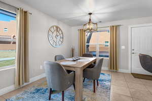 Tiled dining room featuring an inviting chandelier