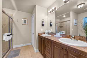 Bathroom with a shower with door, vanity, and tile patterned floors