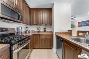 Kitchen with ceiling fan, stainless steel appliances, sink, and light tile patterned flooring