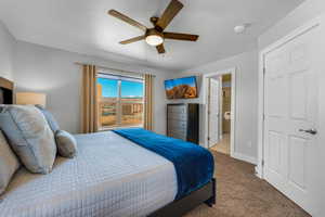 Carpeted bedroom with connected bathroom and ceiling fan