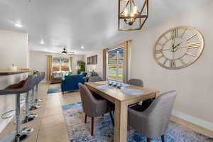 Tiled dining room with ceiling fan with notable chandelier