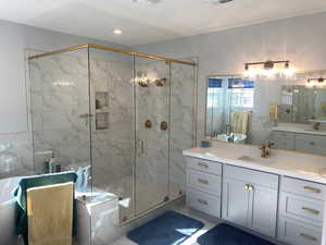 Bathroom featuring vanity, tile walls, and independent shower and bath