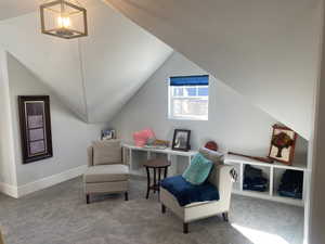 Living area with lofted ceiling, carpet, and a notable chandelier