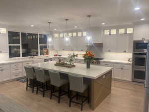 Kitchen with a kitchen bar, a spacious island, white cabinetry, and light hardwood / wood-style flooring