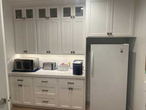 Kitchen featuring white fridge and white cabinetry