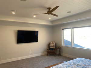 Bedroom with ceiling fan and dark colored carpet