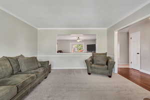 Living room with ceiling fan, ornamental molding, and wood-type flooring